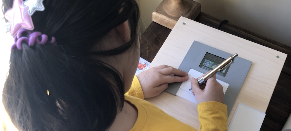 Emma drawing on a CardSong while it sits on top of the FamilySong box